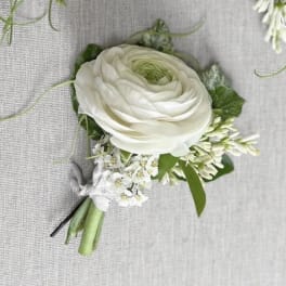 White ranunculus boutonniere with small white accent flowers