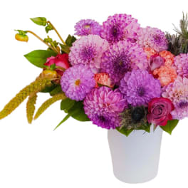 Pink and purple bouquet in a white vase with a few roses and textured blooms
