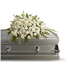 White floral casket spray on a gray casket