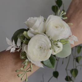 White floral wrist corsage with round blooms and greenery