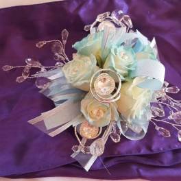 Small pastel floral bouquet with ribbon and crystal accents on purple fabric