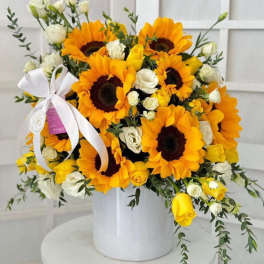 Bouquet of sunflowers and white roses in a white vase with a ribbon