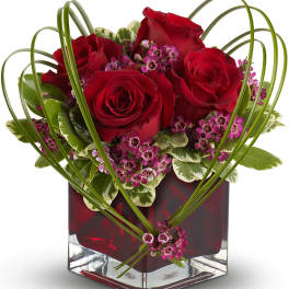 Red roses in a square glass vase with pink filler flowers