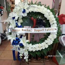 White floral funeral wreath with lilies and blue ribbon