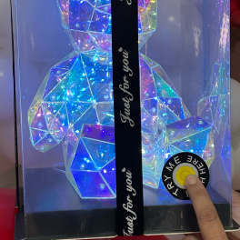 Iridescent geometric teddy bear in a gift box with a ribbon