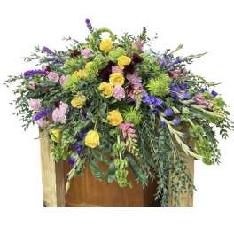 Large mixed floral arrangement with yellow roses, purple blooms, and pink flowers