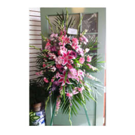 Tall pink and white floral standing spray on a green easel