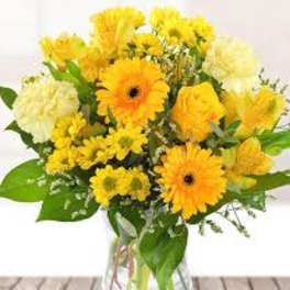 Yellow mixed flower bouquet in a clear glass vase
