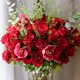 Red roses and pink orchids in a clear glass vase