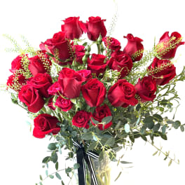 Bouquet of red roses in a clear glass vase with ribbon