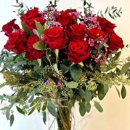 Bouquet of red roses with pink filler flowers in a clear glass vase