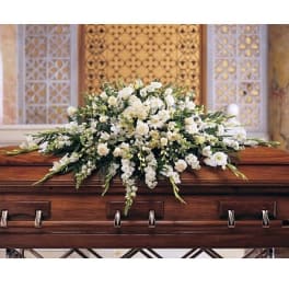 White floral casket spray arranged on a polished wood coffin