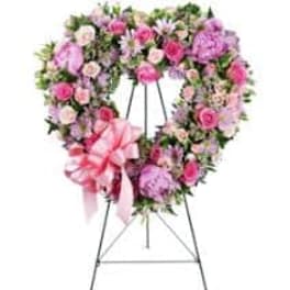 Heart-shaped pink and lavender floral wreath on an easel with a ribbon bow