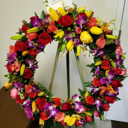 Colorful floral wreath on a stand with a sympathy card