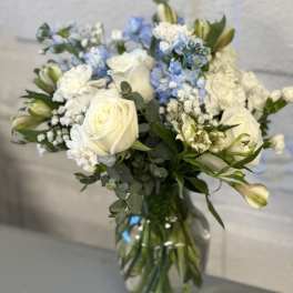 White roses and blue flowers in a glass vase