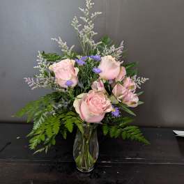 Pink roses and purple flowers in a clear glass vase