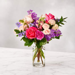 Bouquet of pink and purple roses in a clear glass vase