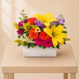 Bright mixed bouquet in a white rectangular box with yellow lilies and roses
