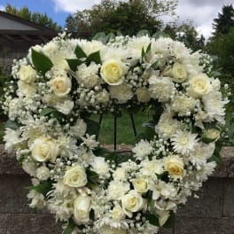 White floral heart wreath with roses and daisies on an easel
