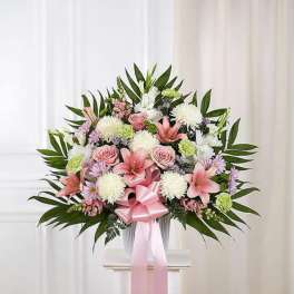 Pink and white floral spray with a ribbon bow on a stand