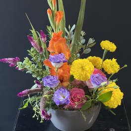 Colorful mixed flower arrangement in a gray bowl vase