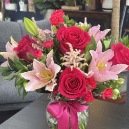 Pink roses and lilies in a glass vase with a ribbon