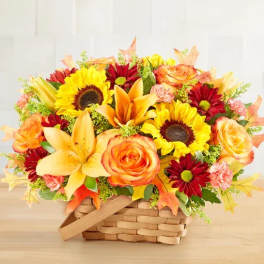 Basket arrangement of sunflowers, roses, lilies, and red daisies