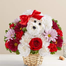 Flower arrangement shaped like a white dog with a red bow in a wicker basket