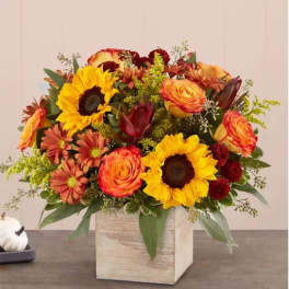Mixed bouquet with sunflowers, roses, and mums in a square wooden vase
