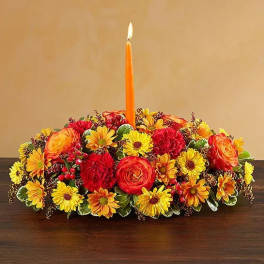Low floral centerpiece with a lit orange taper candle