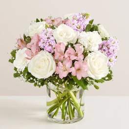 Pink and white flowers arranged in a clear glass vase