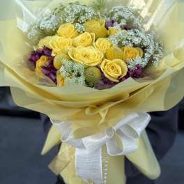Yellow rose bouquet with purple accents and a white ribbon