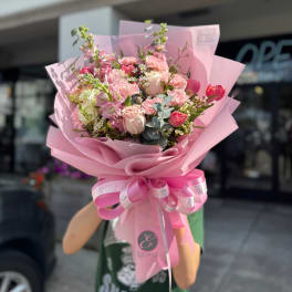 Pink bouquet of roses, tulips, and carnations wrapped in pink paper