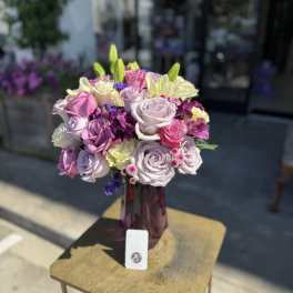 Bouquet of pink, lavender, and cream roses in a purple vase