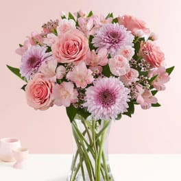 Pink roses and daisies arranged in a clear glass vase