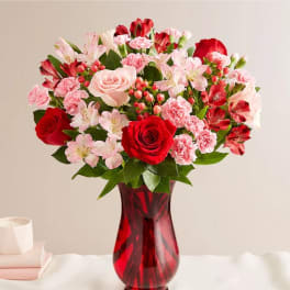 Red and pink mixed bouquet in a red glass vase