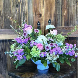 Mixed bouquet of pink, purple, and blue flowers in a blue vase