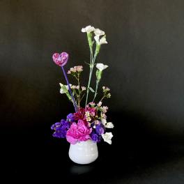 Pink and purple floral arrangement in a white vase