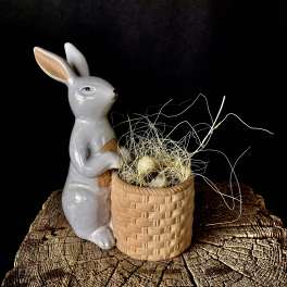 Ceramic rabbit figurine beside a small woven basket with decorative grass