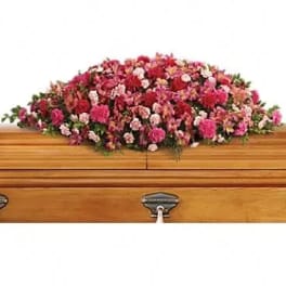 Pink and red floral casket spray on a wooden coffin