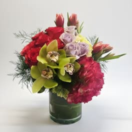 Mixed bouquet of roses, orchids, tulips, and hydrangeas in a glass vase