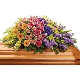Colorful casket spray with pink lilies, roses, and purple flowers