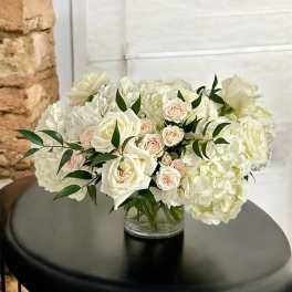 White roses and hydrangeas in a clear glass vase