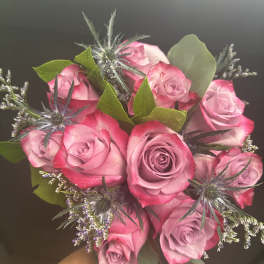 Bouquet of pink roses with spiky blue thistle and greenery