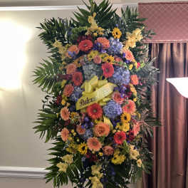 Large standing floral spray with a yellow ribbon and mixed blooms
