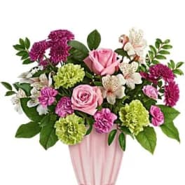 Pink roses and mixed blooms arranged in a pink vase