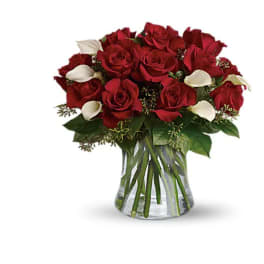 Red roses with white calla lilies in a clear glass vase