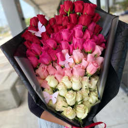 Bouquet of red, pink, and cream roses wrapped in black paper