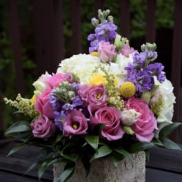 Pink and purple bouquet with white blooms in a square stone vase
