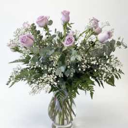 Lavender roses in a clear glass vase with baby's breath